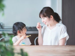 親子で歯磨きをしているところ、幼児とその母親が歯ブラシを持って一緒に歯磨きをしているところ