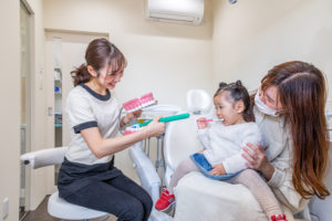 あゆみ歯科クリニックの歯科衛生士が幼児とその保護者に説明をしているところ