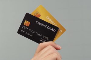クレジットカードのイメージ。グレーの背景で手にクレジットカードを持っている様子