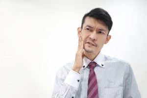 違和感があり頬に手をあてる男性